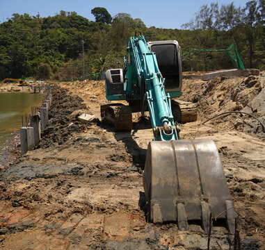 Building process city levee. Excavator dredging pond bank