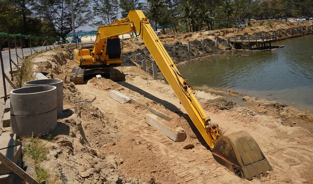 Building process city levee. Excavator dredging pond bank