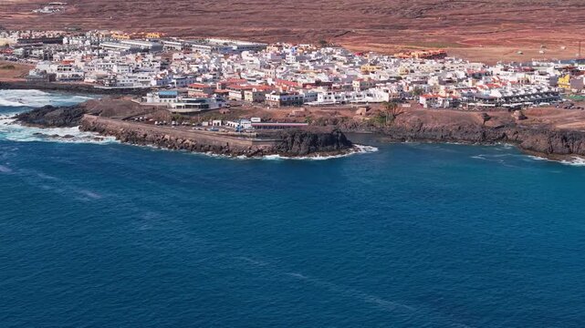 Aerial view of surroundings from El Cotillo, a coastal town located on the island of Fuerteventura, Canary Islands, Spain. Drone POV exploration of the coastal town structure and the ocean beach.