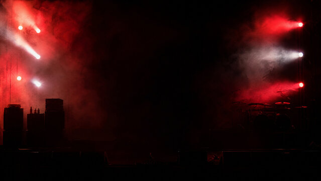 Dramatic red stage lighting with smoke effect, concert spotlight beams on dark background, theatrical performance atmosphere