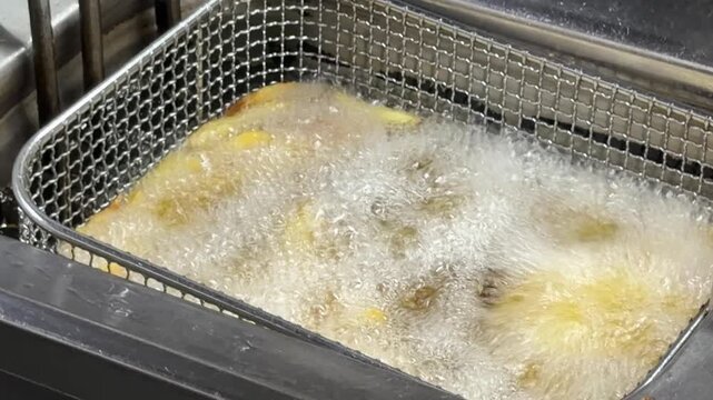French fries cooking in a commercial deep fryer basket