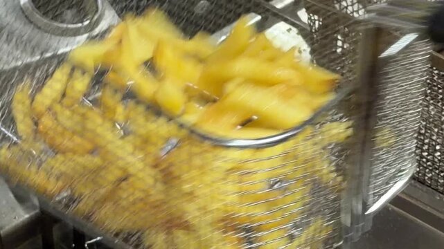 Chef cooking golden french fries in deep fryer basket