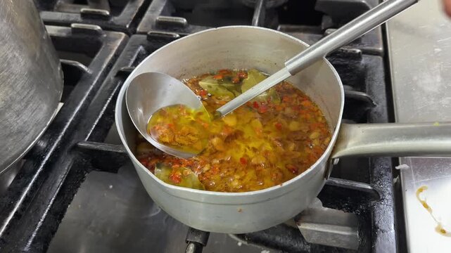Chef stirring hot spicy chili oil in a professional kitchen