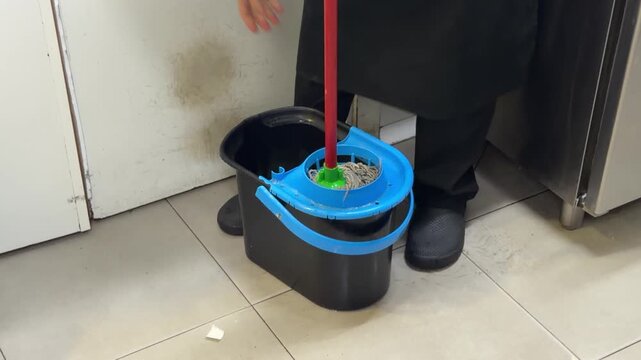 Professional cleaner wringing a mop in a bucket