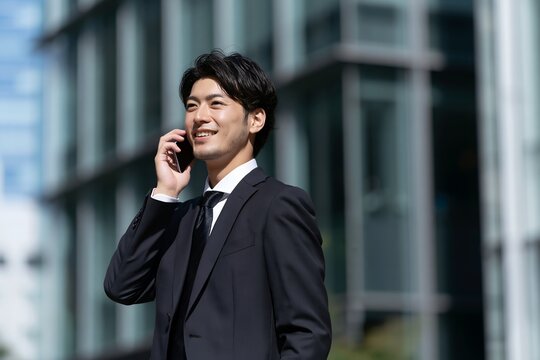 笑顔のビジネスマンが都市でスマートフォンで電話する