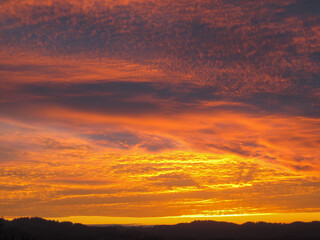 Fototapeta premium Fiery Orange Sunset Beneath Dramatic Textured Clouds