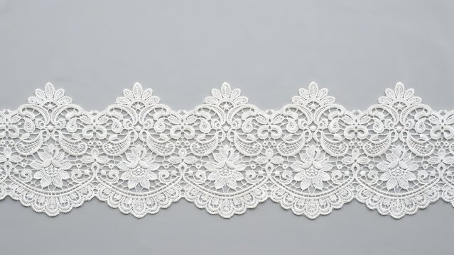 Intricate white lace trim with floral patterns and scalloped edges on a gray background