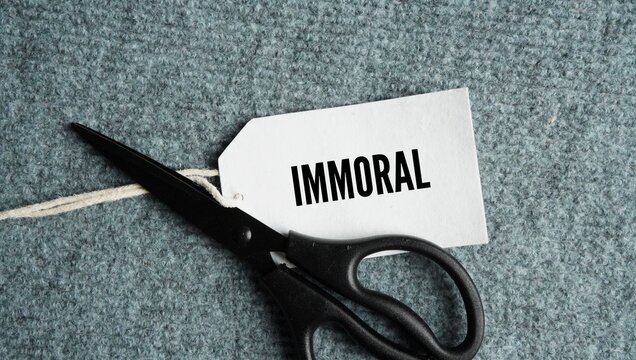 Scissors and paper tags with the words immoral. actively going against accepted standards of right, wrong, and ethical behavior.