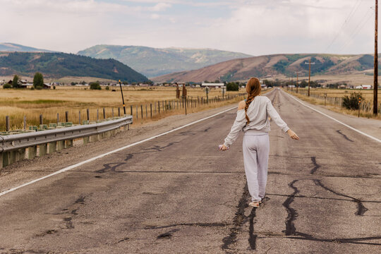 Woman walks alone down a long country road