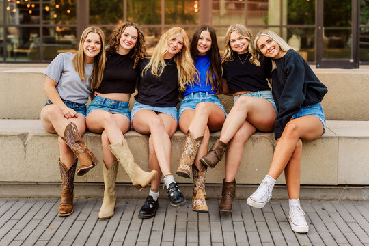 Happy young friends in cowboy boots sit together