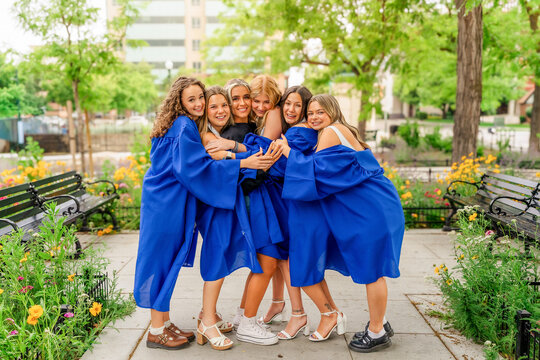 Group of happy female graduates hugging outdoors