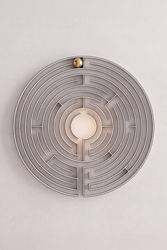 A modern illuminated circular wall maze sculpture with a glowing center and a gold sphere