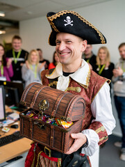 Naklejka premium Man in pirate costume and tricorn hat holding treasure chest filled with candies for Halloween