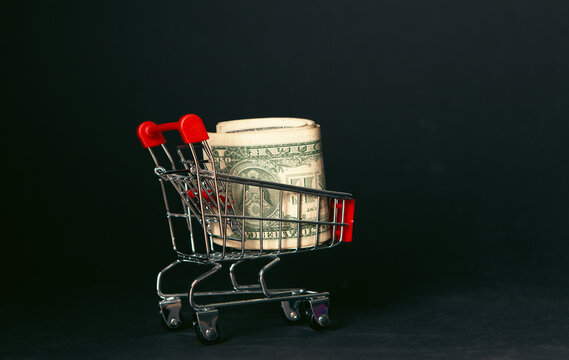 Shopping cart with dollar banknote on black background,