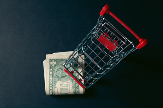 Shopping cart with dollar banknote on black background,