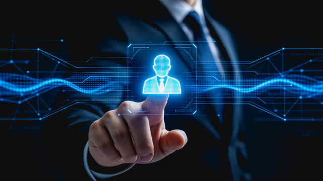 A suited businessperson touches a glowing digital user icon on a futuristic virtual interface, representing modern business tech interaction.