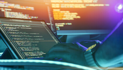 Programmer Working with Source Code on Multiple Computer Screens