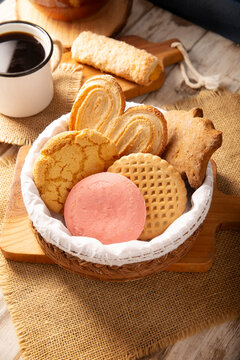 Traditional Mexican sweet bread variety on a rustic wooden board. Variety of authentic pan dulce including puerquito, orejas, and cookies over a neutral tablecloth background for bakery concept.