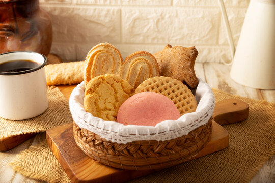 Traditional Mexican sweet bread variety on a rustic wooden board. Variety of authentic pan dulce including puerquito, orejas, and cookies over a neutral tablecloth background for bakery concept.