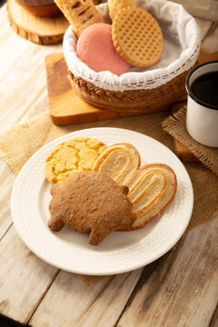 Traditional Mexican sweet bread variety on a rustic wooden board. Variety of authentic pan dulce including puerquito, orejas, and cookies over a neutral tablecloth background for bakery concept.