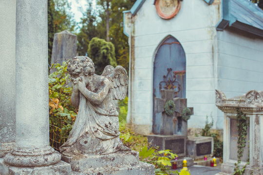 Ancient cemetery monuments featuring ornate gravestones, weathered stone sculptures and historic tombs surrounded by trees. Atmospheric old-world funerary architecture and timeless memorial details 