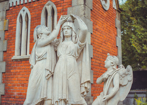 Ancient cemetery monuments featuring ornate gravestones, weathered stone sculptures and historic tombs surrounded by trees. Atmospheric old-world funerary architecture and timeless memorial details 