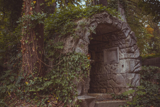Ancient cemetery monuments featuring ornate gravestones, weathered stone sculptures and historic tombs surrounded by trees. Atmospheric old-world funerary architecture and timeless memorial details 