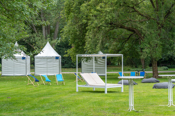 White cabana daybed and pagoda tents in a leafy park © Jakob