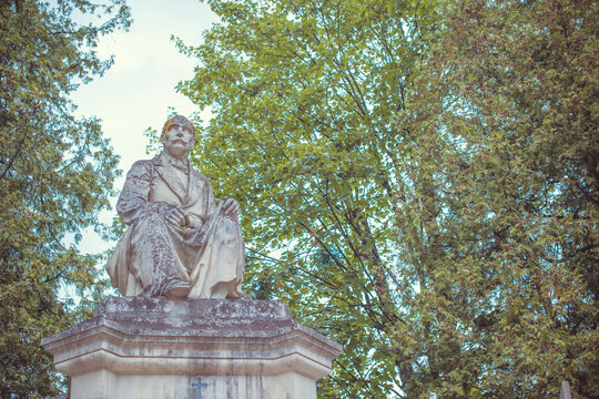 Ancient cemetery monuments featuring ornate gravestones, weathered stone sculptures and historic tombs surrounded by trees. Atmospheric old-world funerary architecture and timeless memorial details 