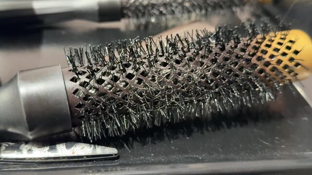 Several professional radial brushes with vented barrels lie together at a hairdresser workspace, ready for blow drying, shaping and salon hairstyling. Close up.