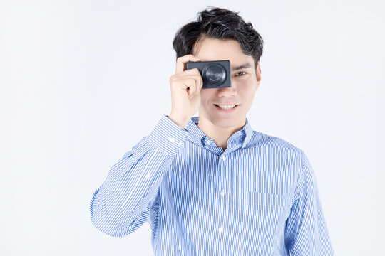 Smiling young man taking a photo with compact camera in studio