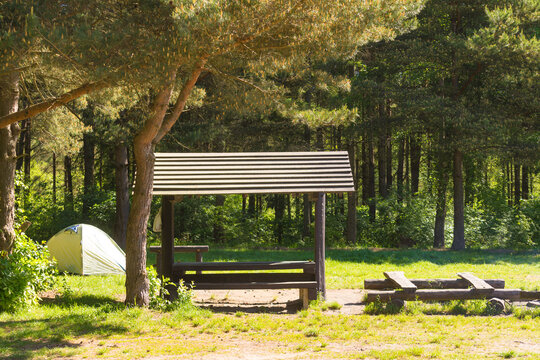 Camping in the woods with a tent and picnic shelter during a sunny day