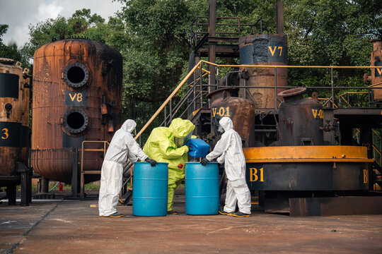 Hazmat team transferring liquid from a chemical container into storage drums during hazardous materials handling and emergency response training at an outdoor industrial facility