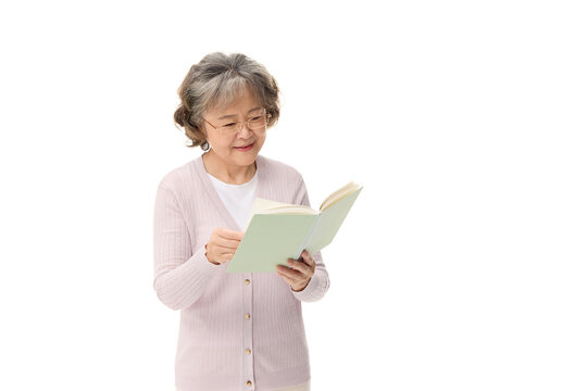 Smiling senior Asian woman reading a book on white background