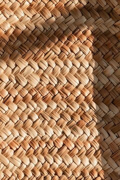 Closeup of woven raffia basket texture illuminated by warm afternoon light, showcasing natural palm fiber weave and color variations