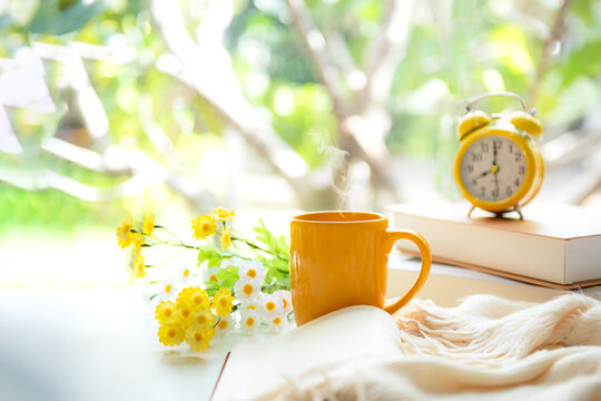 Coffee morning.  Yellow steaming cup of hot coffee for relax after working hobbies crochet on white wooden near window with flowers
