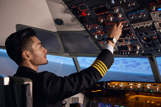 Airline Pilot Operating Controls in Airplane Cockpit