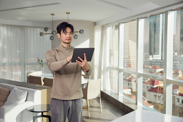 Man Controlling Smart Home Devices with Tablet in Modern Apartment © LeNgoc