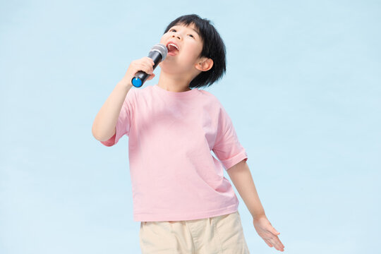 Happy young child singing with microphone on blue background