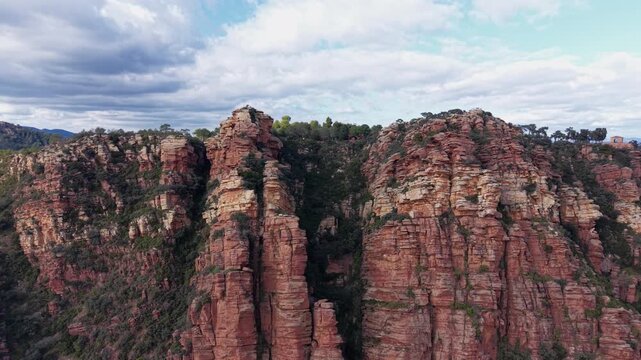 Dramatic red sandstone cliffs at Mirador de Garbi, highlighting rugged rock formations and forested slopes in the Sierra Calderona Natural Park, Valencia, Spain