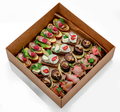 Variety of small dishes in a takeout box. A takeout box filled with small dishes featuring meats, seafood, and toppings. Different flavors are seen together.