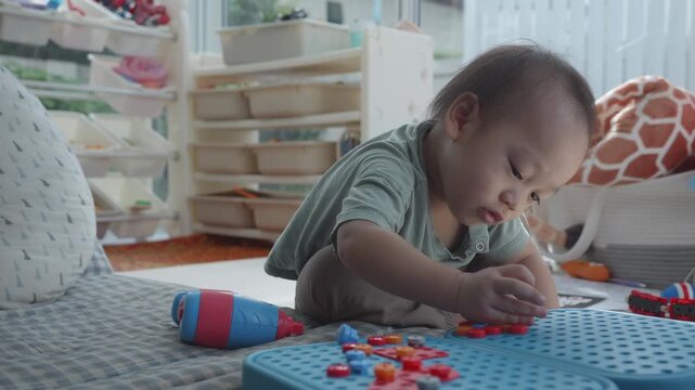 A young child focuses intently on assembling colorful building blocks in a playful environment, showcasing creativity and concentration. The bright setting encourages exploration and fun.