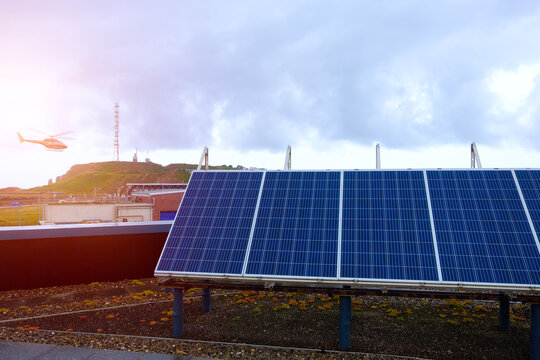 Solar Panel Array with Helicopter Flying Over Coastal Industrial Landscape