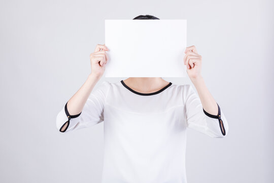 Woman Holding Blank White Paper Covering Face in Studio