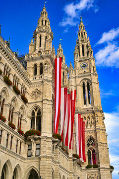 Majestic neo-Gothic facade of the Vienna City Hall with national flags of Austria under a blue sky, Vienna