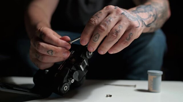 Close up of a tattooed man repairing an old analog film camera. Professional technician servicing a vintage slr device in his workshop