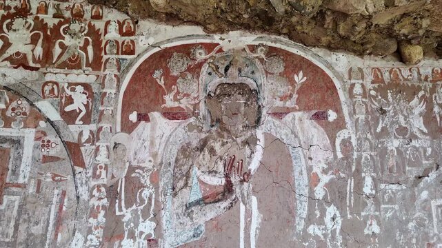 Saspol, India : Tilt down footage of Buddha wall paintings dating from 13th to 15th centuries located in Saspol cave, famous ancient Buddhist temple in the cliff of Saspol village of Ladakh, India
