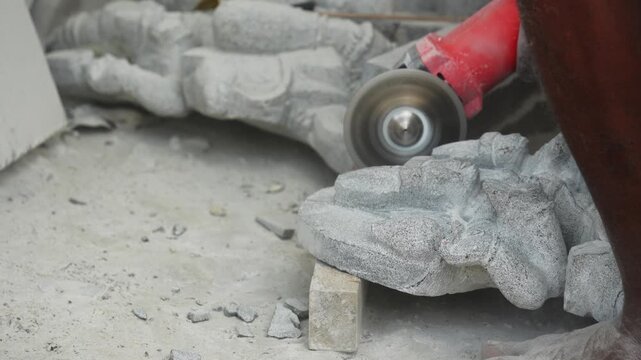 Sculptor shaping carved stone hand sculpture with angle grinder 