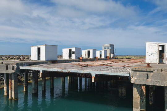 Concrete pier dock structure overlooking ocean under blue sky