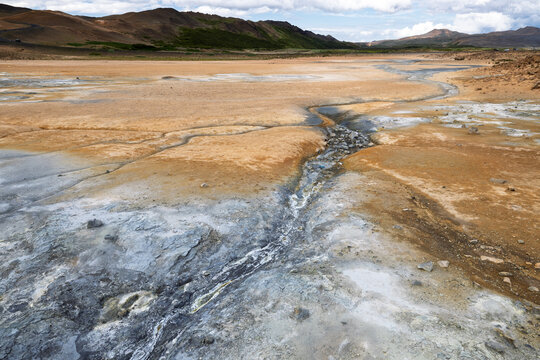 Geothermal mud pool area with steam vents and yellow sulfur soil